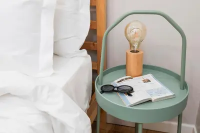 a bedside table with a lamp and a book and a light bulb at Trevi Fountain Apartment - ZENO 03 in Rome