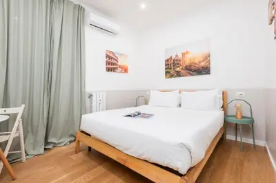 a bedroom with a bed with white sheets and a table at Trevi Fountain Apartment - ZENO 03 in Rome