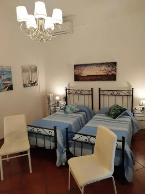 two beds in a room with two chairs and a chandelier at Almachiara in Rome
