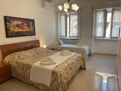 a bedroom with two beds and a table and windows at Roma Apartment in Rome