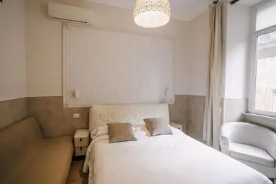 a bedroom with a white bed and a chair at Walker Rooms in Rome