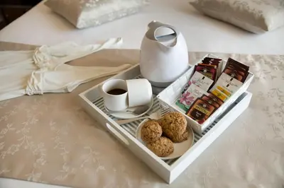 a tray with a cup of coffee and cookies on a bed at Unicum Roma Suites in Rome