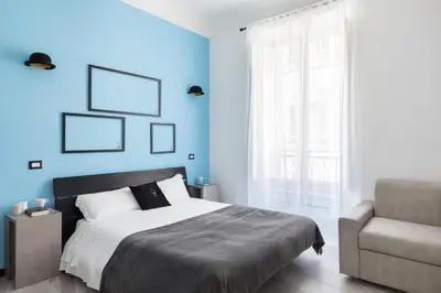 a bedroom with blue walls and a bed and a chair at A World Aparts - 23 Artisti in Rome
