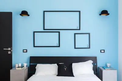 a bedroom with a blue wall and a bed with two frames at A World Aparts - 23 Artisti in Rome