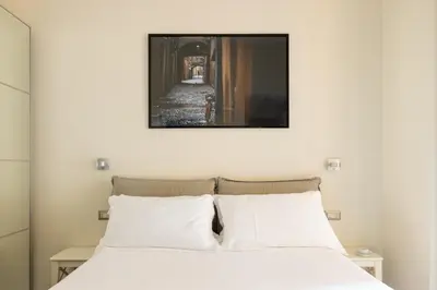 a bedroom with a white bed with a picture above it at HospitalityRome Domus Aureliana in Rome