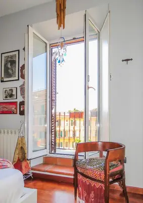 a room with a chair and a large window at House Candia 111 - Vatican Museum apartment in Rome