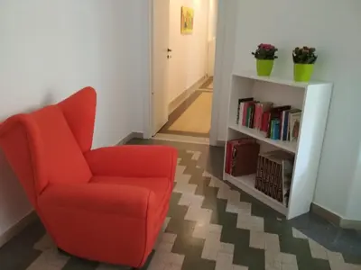 a living room with a red chair and a book shelf at B&B Una notte a Mazzini in Rome