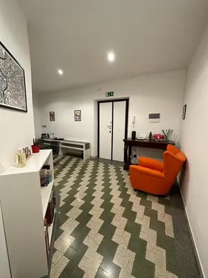 a living room with an orange chair and a kitchen at B&B Una notte a Mazzini in Rome