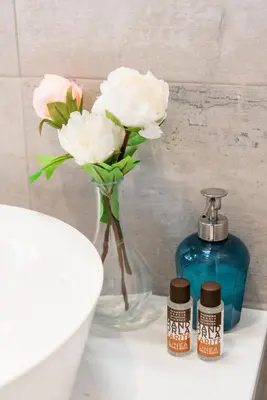 a vase with white flowers and a bottle of soap at Winkler Suites in Rome