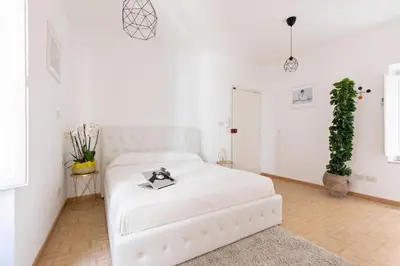 a white bedroom with a white bed and a plant at Presidential Penthouse Navona in Rome