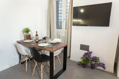 a dining room table with white chairs and a tv at Testaccio historic house in Rome