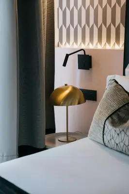 a gold lamp on a table next to a bed at NAMAN HOTELLERIE - Margutta in Rome