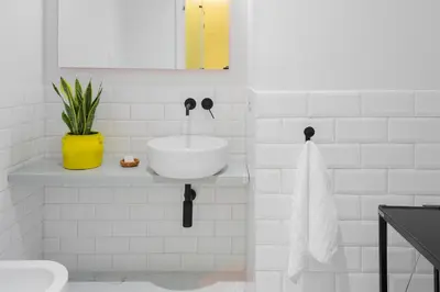 a white tiled bathroom with a sink and a toilet at The Radical Hotel Roma in Rome