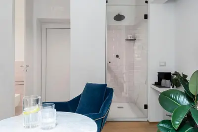 a room with a table and a blue chair and a shower at The Radical Hotel Roma in Rome