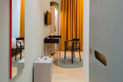 a room with a table with a chair and orange curtains at The Radical Hotel Roma in Rome