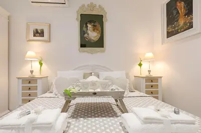 a white bedroom with a large bed with two dressers at Cave98 Apartment in Rome