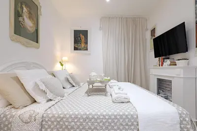 a white bedroom with a white bed with a fireplace at Cave98 Apartment in Rome