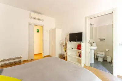 a white bedroom with a bed and a bathroom at St. Peter Garden House in Rome