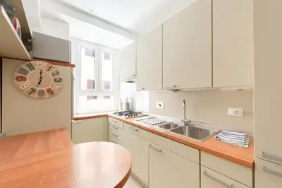a kitchen with white cabinets and a clock on the wall at Saint Peters Luxury 3 Bedrooms Apartment in Rome