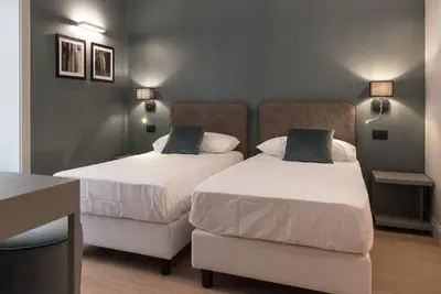 a room with two beds and a desk and two lamps at Domus Alberico in Rome
