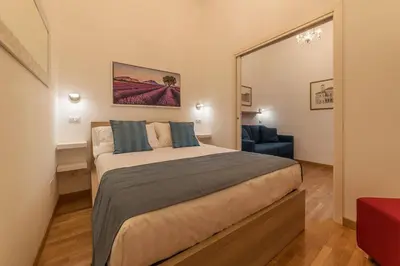a bedroom with a large bed and a blue chair at CS Termini Nazionale Apartments in Rome