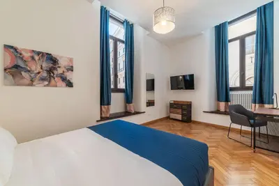 a bedroom with a bed and a desk and windows at CS Termini Nazionale Apartments in Rome