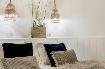 a living room with a couch with pillows and two lights at Trastevere Gem Cozy Light-filled Retreat in Rome