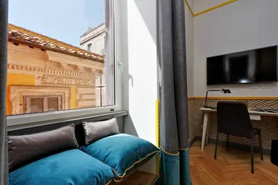 a room with a window with a couch and a table at Roma Five Suites in Rome