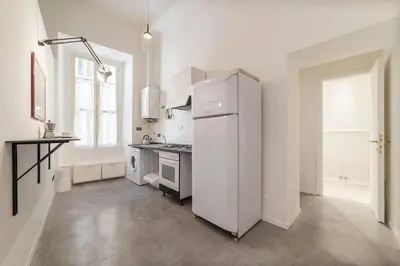 a white kitchen with a refrigerator and a window at Loft Farnese soggiorno 2 stanze 2 bagni luxury centro in Rome