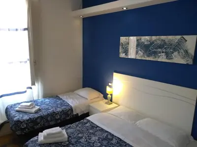 a bedroom with two beds and a blue wall at Vatican Room and Kitchen in Rome