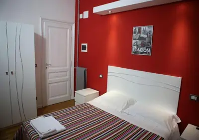 a bedroom with a red wall with a bed at Vatican Room and Kitchen in Rome