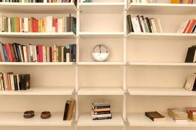 a book shelf with a clock and books at Virgiliano Apartment in Rome
