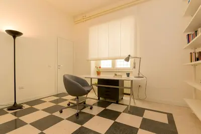 a desk and a chair in a room with a checkered floor at Virgiliano Apartment in Rome