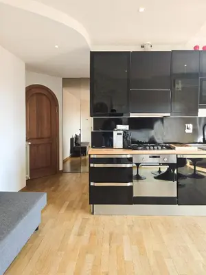 a kitchen with black and white cabinets and wooden floors at Panoramic Sunset Terrace Attic in Rome