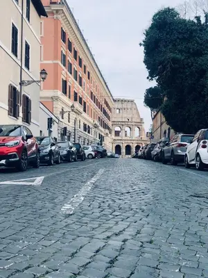 a cobblestone street with parked cars and buildings at COLOSSEUM STREET HoMe in Rome