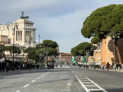 an empty city street with people walking on the sidewalk at COLOSSEUM STREET HoMe in Rome