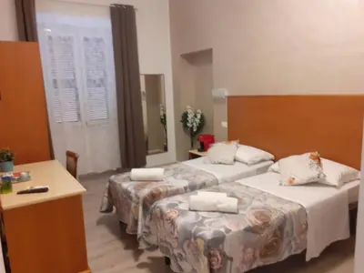 a hotel room with two beds and a desk at Napoleone Luxury Home roma in Rome