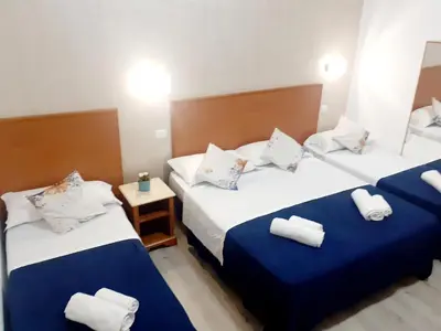 a hotel room with two beds with blue and white sheets at Napoleone Luxury Home roma in Rome