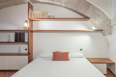 a bedroom with a white bed and a brick wall at Roman Forum Cozy Apartment in Rome