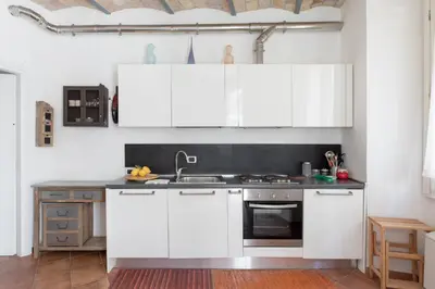a kitchen with white cabinets and a sink at Roman Forum Cozy Apartment in Rome