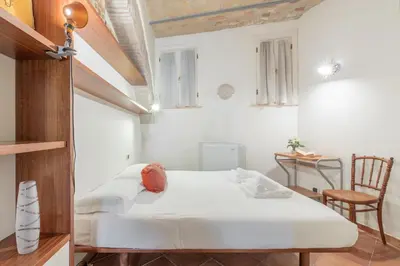 a bedroom with a white bed and a chair at Roman Forum Cozy Apartment in Rome
