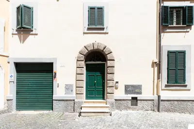 a building with green doors and two windows at Roman Forum Cozy Apartment in Rome