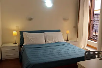 a bedroom with a bed with blue sheets and two lamps at Aida Trevi Fountain Rome in Rome