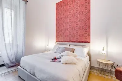a bedroom with a large white bed with a red wall at BDC - Termini Sun Apartment in Rome