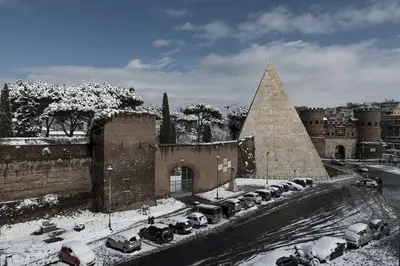 a building with cars parked in a parking lot covered in snow at LUMINOSA VISTA PIRAMIDE in Rome