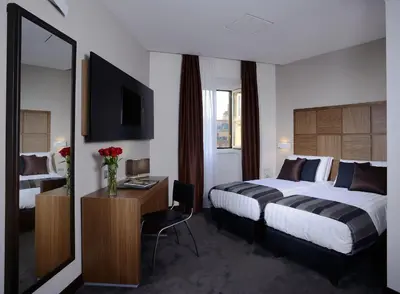 a hotel room with a bed and a desk with a mirror at Rome Art Hotel - Gruppo Trevi Hotels in Rome