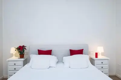 a white bed with red pillows in a white bedroom at Vatican Quiet Apartment with Garden & Parking in Rome