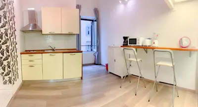 a kitchen with white cabinets and a counter with stools at Luxury barberini boutique Apartment in Rome