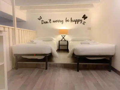 two beds in a room with a sign that says dont worry be happy at Luxury barberini boutique Apartment in Rome