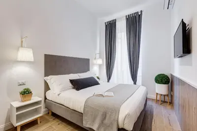 a white bedroom with a large bed and a television at Germanico Luxury Apartment in Rome